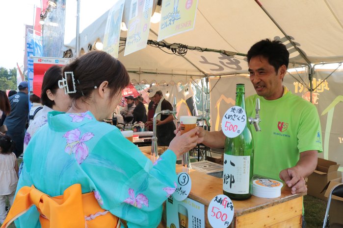 屋台で大山地ビールを注文する浴衣姿の女性